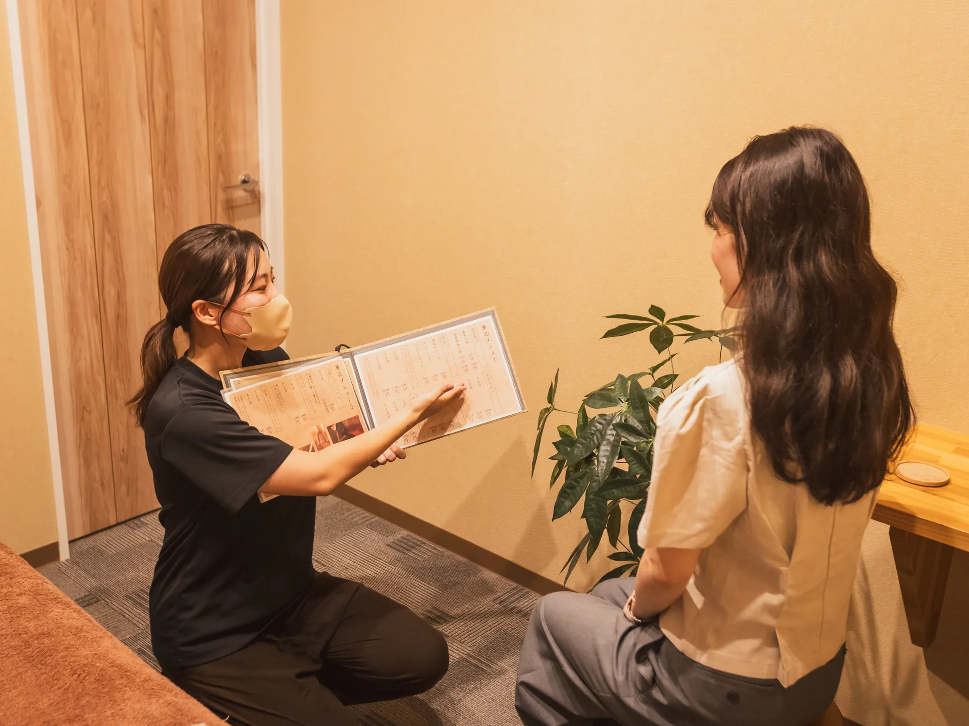 メニュー表を開きながらカウンセリングをするセラピストとお客様